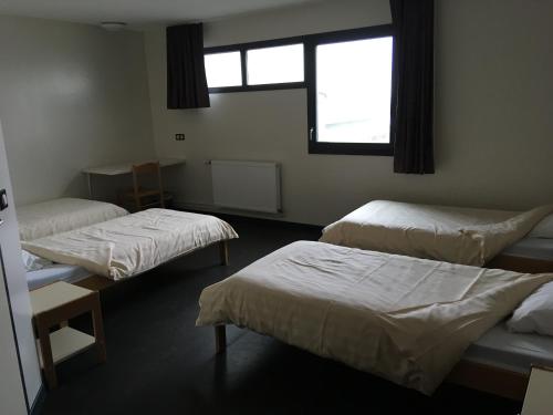 a room with three beds and a window at Auberge de jeunesse L'Escale in Dunkerque