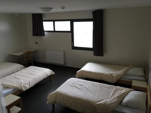 a room with three beds and a window at Auberge de jeunesse L'Escale in Dunkerque