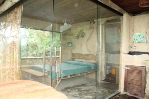 a bedroom with a bed and a glass wall at Canto de Paz Trindade Hospedagem in Trindade