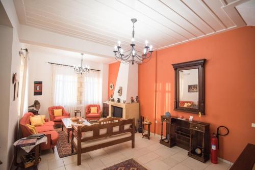 a living room with orange walls and a chandelier at Katalagari Country Suites in Archanes