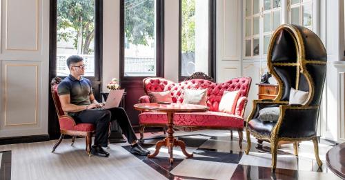 a man sitting in a chair in a room with a laptop at A.LIST HOTEL in Songkhla