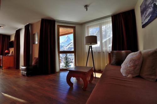 a living room filled with furniture and a window at Alpenlodge in Zermatt