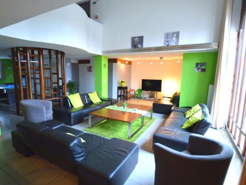 uma sala de estar com mobiliário preto e uma parede verde em Charming farmhouse in Waimes with swimming pool and sauna em Waimes
