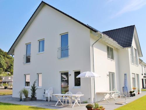 a white house with tables and chairs and an umbrella at FeWo WELL in Gladenbach