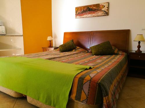 Un dormitorio con una cama grande con una manta verde. en Porto Mos Residence, en Lagos