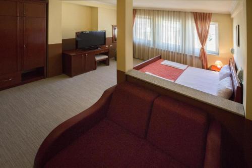 una camera d'albergo con un letto e una TV a schermo piatto di Hotel Atlas a Novi Pazar