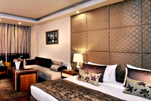 a hotel room with a bed and a couch at Udman Hotel Panchshila Park in New Delhi