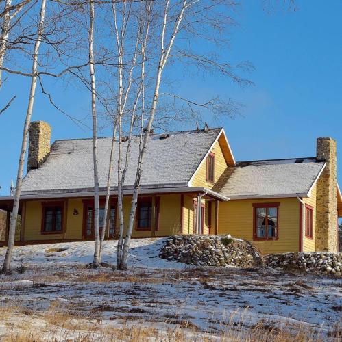 a yellow house with trees in front of it at Le Champ Perché in La Malbaie