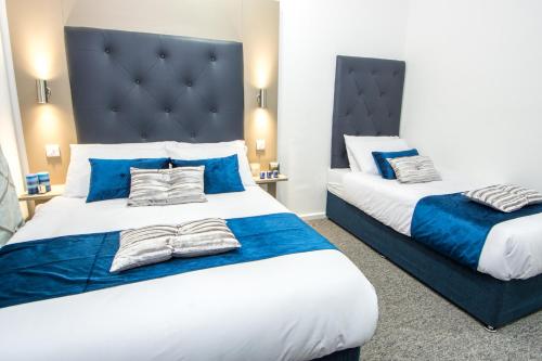 two beds in a hotel room with blue accents at Abbey Hotel in Leicester