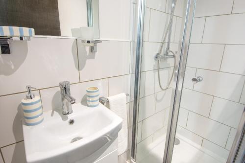 a white bathroom with a sink and a shower at Abbey Hotel in Leicester