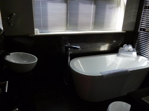 a bathroom with a tub and a sink and a window at Aston Hall Hotel, BW Signature Collection in Sheffield