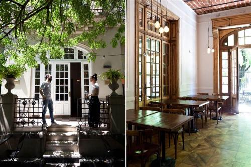 dos personas de pie en un restaurante con mesas en Hotel De La Rue en Buenos Aires