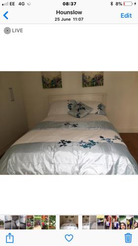 a bed with white sheets and blue flowers on it at House in Hounslow