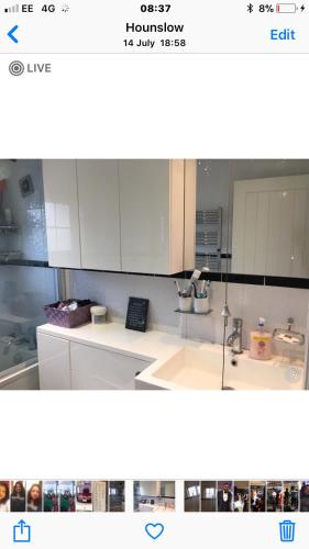 una imagen de una cocina con armarios blancos en House en Hounslow