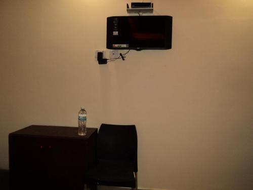 a room with a chair and a television on a wall at Mani's residency in Madurai