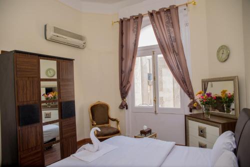 a bedroom with a bed and a chair and a window at Hotel Grand Royal Cairo in Cairo