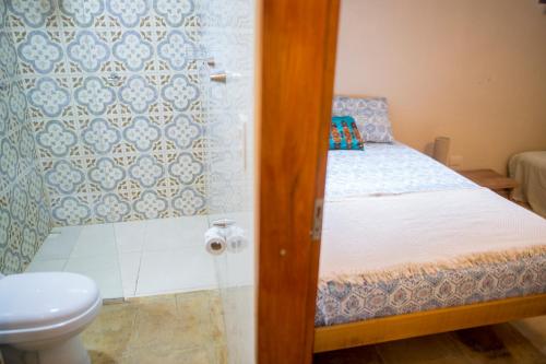 a small bathroom with a bed and a toilet at Casa Bougainvilla in Jericoacoara