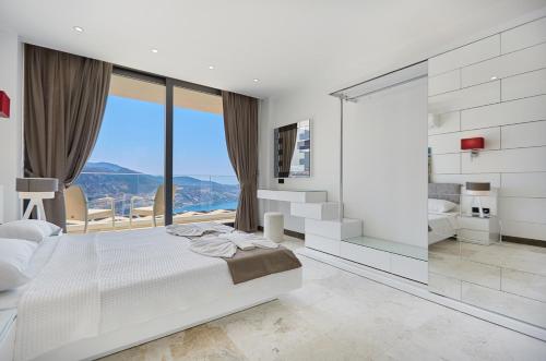 a white bedroom with a large bed and a large window at Villa Unlimited 5 Bedroom Luxury Villa with Infinity Pool in Kalkan