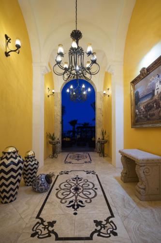 a living room with a chandelier and a room with a table at El Encanto All Inclusive Resort in Cabo San Lucas