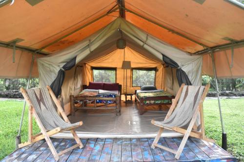 a tent with two chairs and a table in it at Red Rocks Rwanda - Campsite & Guesthouse in Nyakinama