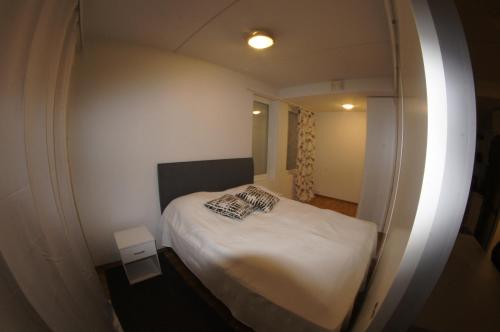 una piccola camera con letto bianco e specchio di Sarastus a Tornio