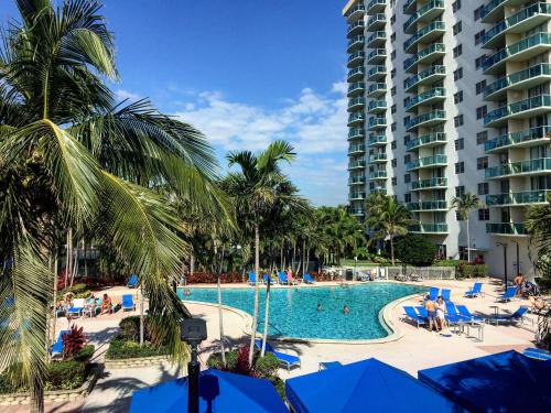 a pool at a resort with palm trees and a building at Ocean Reserve Miami Luxury Rentals in Sunny Isles Beach
