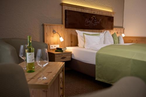 a hotel room with a bed and two glasses of wine at Hotel Tyrol in Oberstaufen