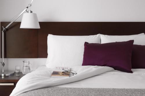 a bed with a lamp and a book on it at Real Colonia Hotel & Suites in Colonia del Sacramento