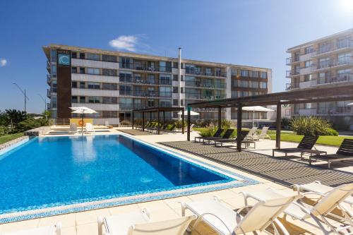 a swimming pool with chairs and a building at Real Colonia Hotel & Suites in Colonia del Sacramento