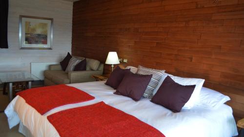 a bedroom with a large bed and a couch at Kila Tai Tai Lodge in Curarrehue