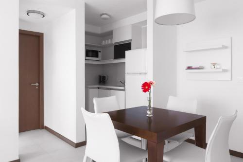 a dining room with a wooden table and white chairs at Real Colonia Hotel & Suites in Colonia del Sacramento