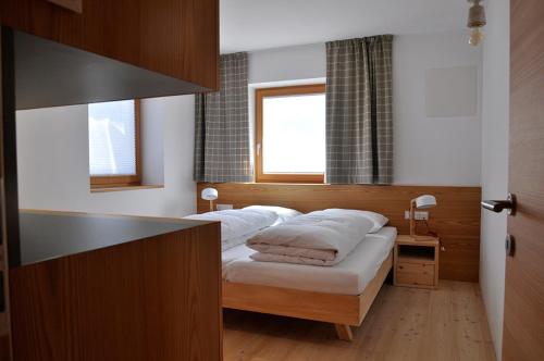 a bedroom with a bed with white sheets and a window at Apartments Frieda in Valdaora