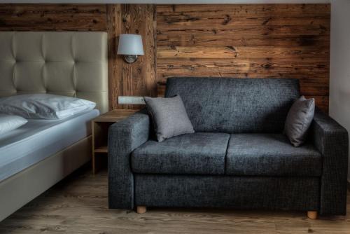 a couch in a bedroom next to a bed at Hotel Krondlhof in Brunico