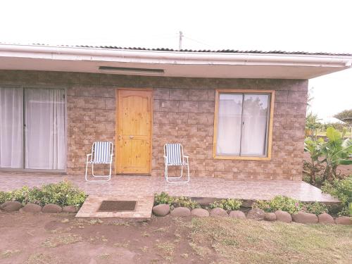 a brick house with two chairs and a door at Cabaña Tongariki in Hanga Roa