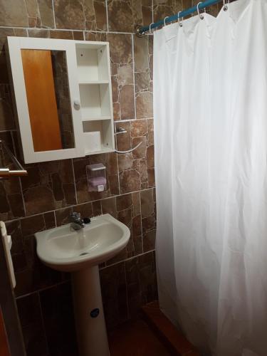 a bathroom with a sink and a white shower curtain at Cabaña Tongariki in Hanga Roa