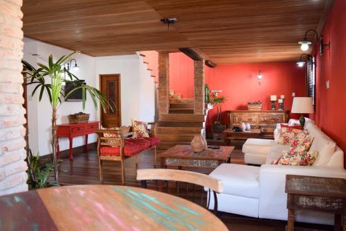 salon z białą kanapą i czerwonymi ścianami w obiekcie Pousada Bela Cigana w mieście Conservatória