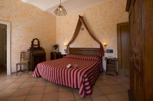 a bedroom with a bed with a red and white striped blanket at Agriturismo Palazzo Bandino - Wine cellar, on reservation restaurant and spa in Chianciano Terme