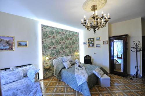 a bedroom with a bed and a couch and a chandelier at B&b Le Cycas in Castellammare di Stabia