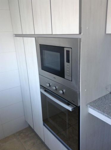a microwave oven in a kitchen with white cabinets at Condominio Costa Peñuelas in Coquimbo