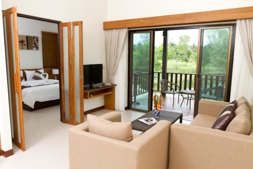 a living room with two chairs and a bed and a television at Khaolak Blue Lagoon Resort - SHA Extra Plus in Khao Lak