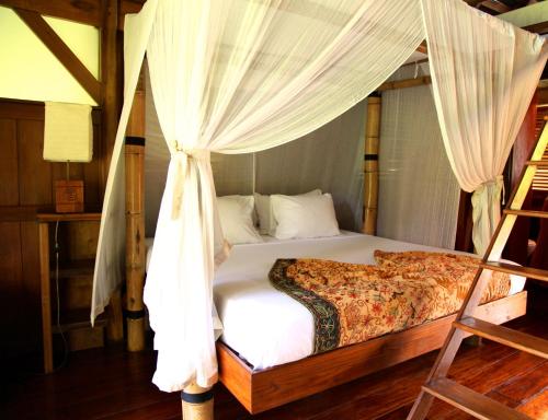 a bedroom with a bed with a canopy at Acajou Hotel in Grande Riviere