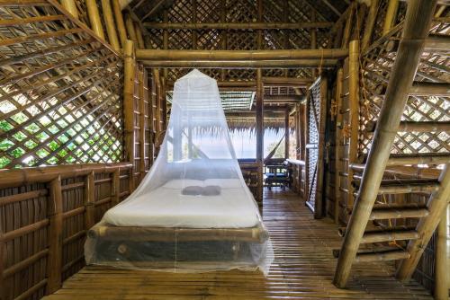 eine Hängematte in einem Bambuszimmer mit einem Bett darin in der Unterkunft Kookoo's nest eco-lodge in Siaton