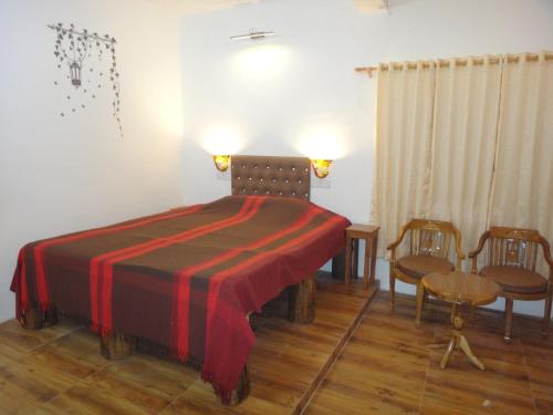 a bedroom with a bed with a red blanket and chairs at Aqua De Vida in Bhowāli