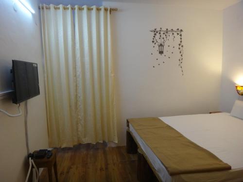 a small bedroom with a bed and a television at Aqua De Vida in Bhowāli