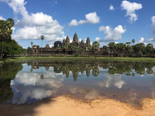 a reflection of a temple in the water of a lake at Eco-Home Siem Reap Homestay in Siem Reap