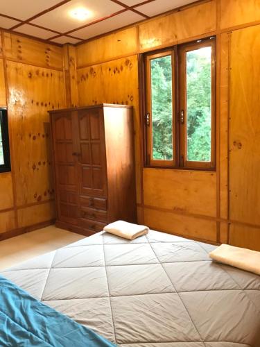 a bedroom with a large bed in a room with windows at Kiri Tawan in Baan Tai