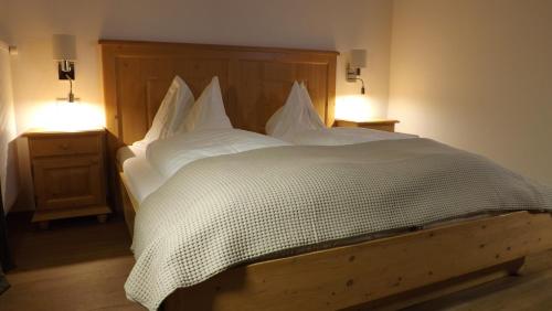 a bedroom with a bed with white sheets and two lights at Pension Geissler-Reicher in Oberwölz Stadt