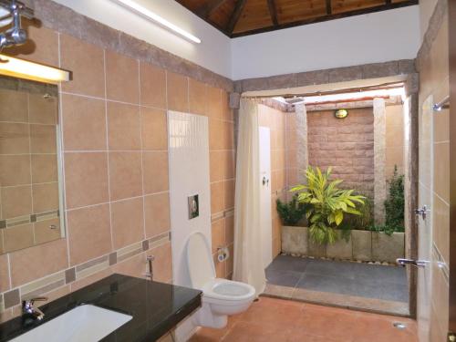 a bathroom with a toilet and a sink and a shower at Kadambavanam Ethnic Village Resort in Pālamedu