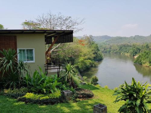 a house with a balcony next to a river at Kwainoy Riverpark in Sai Yok