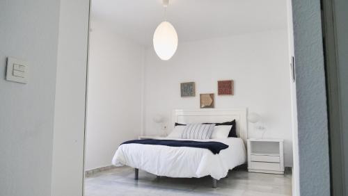a white bedroom with a white bed and a mirror at Casinomar Frente al Mar in Benalmádena